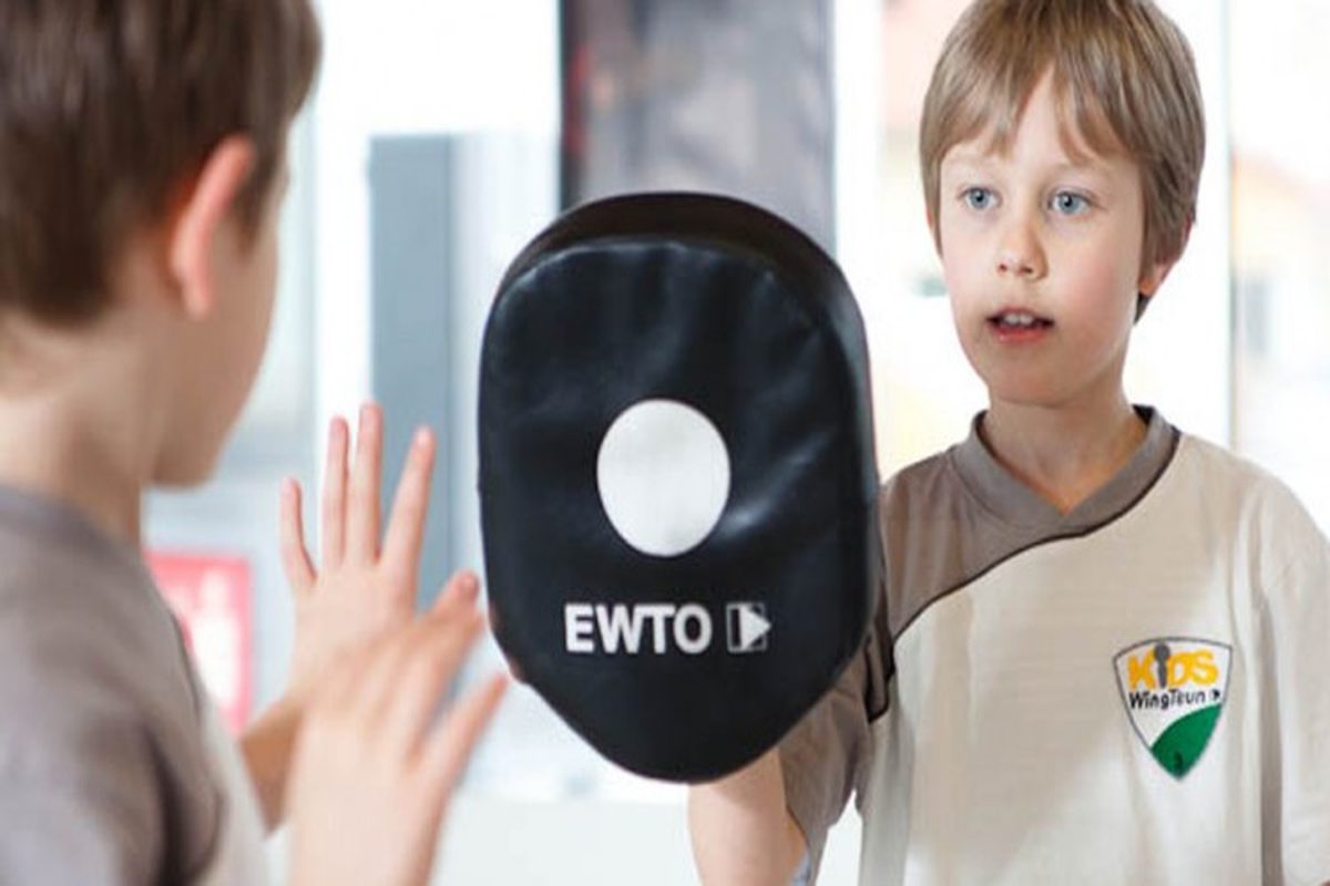 Kinder WingTsun Training in Neuss: Junge übt Schlagtechnik mit Pratze und Trainer